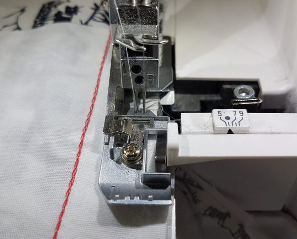 guiding the fabric edge along the stitch plate edge
