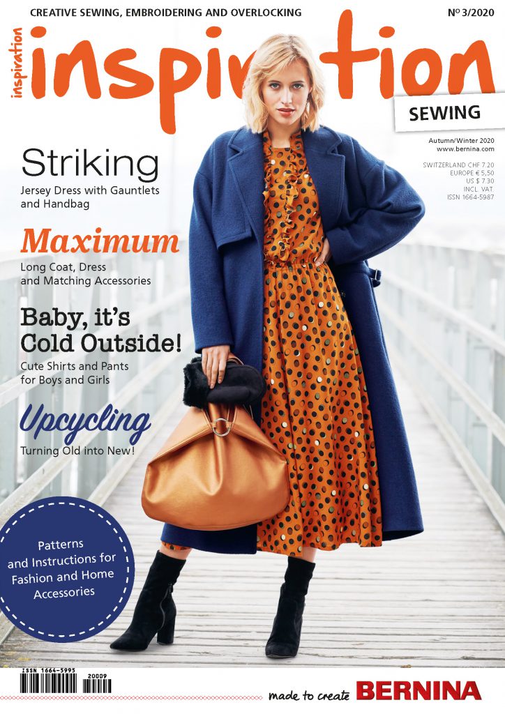 autumn/winter 2020 issue of "inspiration", featuring a blond model with a curly long bob haircut, an orange and blackspotted Maxi dress, a blue coat, black boots and carrying a bigger handbag out of orange leather and black gloves in her right hand.