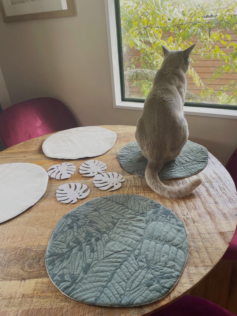 table setting of four placemats with a cat looking out the window