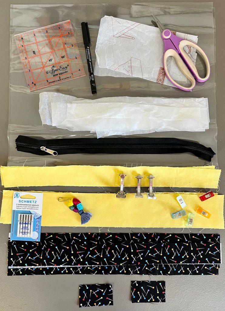 Supplies for vinyl project bag, ruler, fabric clips, #51 Roller Foot, #37 Patchwork Foot, #39 Open/Closed Embroidery Foot, #52 Zigzag Foot with sliding sole, vinyl, tissue paper, permanent marker, lightweight fusible interfacing, #5 zipper, accent fabric, lining, sewing clips, schmetz Non slip #80 Needles, zipper pull, BERNINA #350 PE